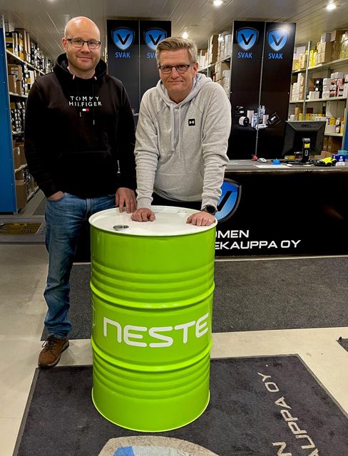 Tommi Uusi-Rauva ja Tapio Laine poseeraavat myymälässä Neste-tynnyrin kanssa.