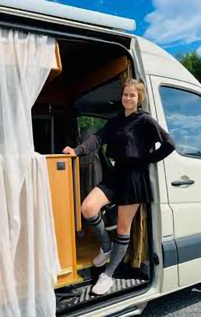 Nina Laitiala poseeraa matkailuauton sivuovella.