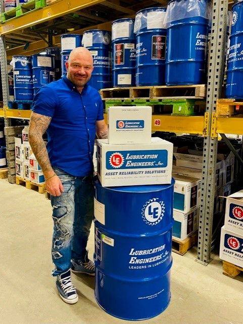 Tony Hakovirta poseeraa varastossa Lubrication Engineers -tuotteiden kanssa.