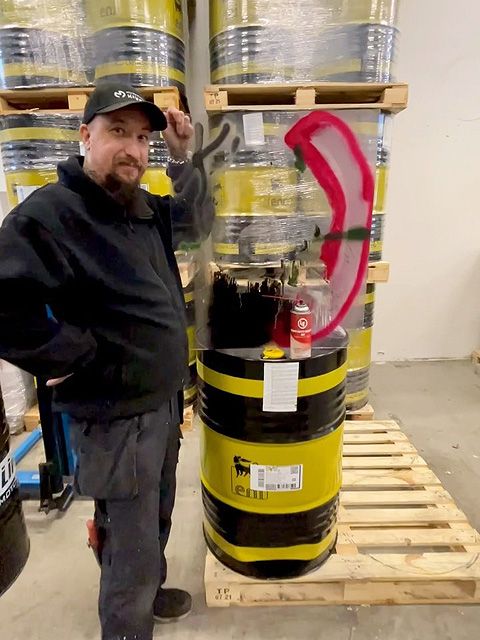 Jari Kivelä poseeraa varastossa, käsissään LE802-spraypurkki ja osittain töhryistä puhdistettu pleksi.